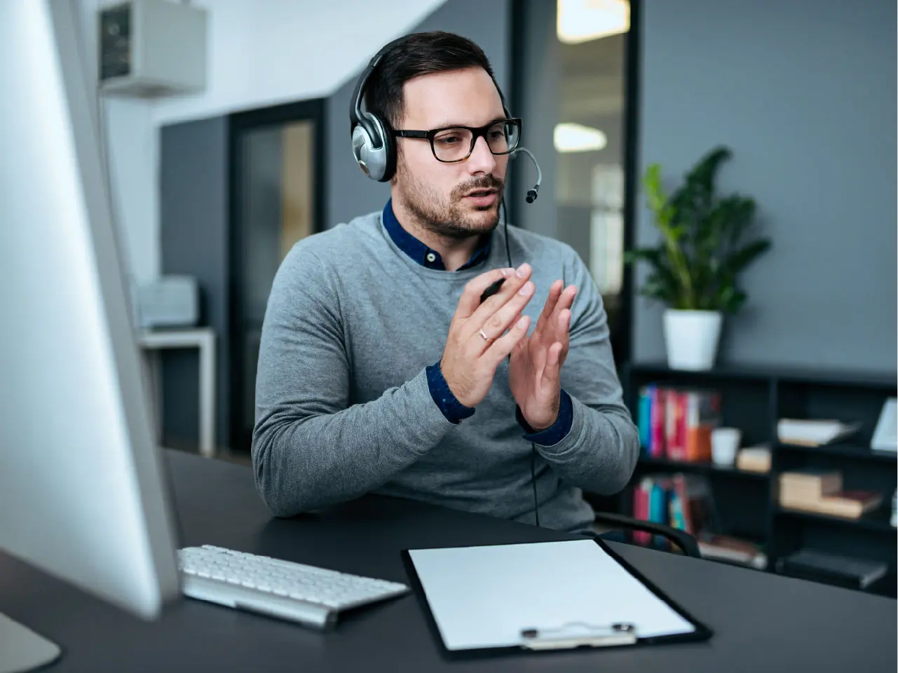 A man wearing a headset in front of a computer.